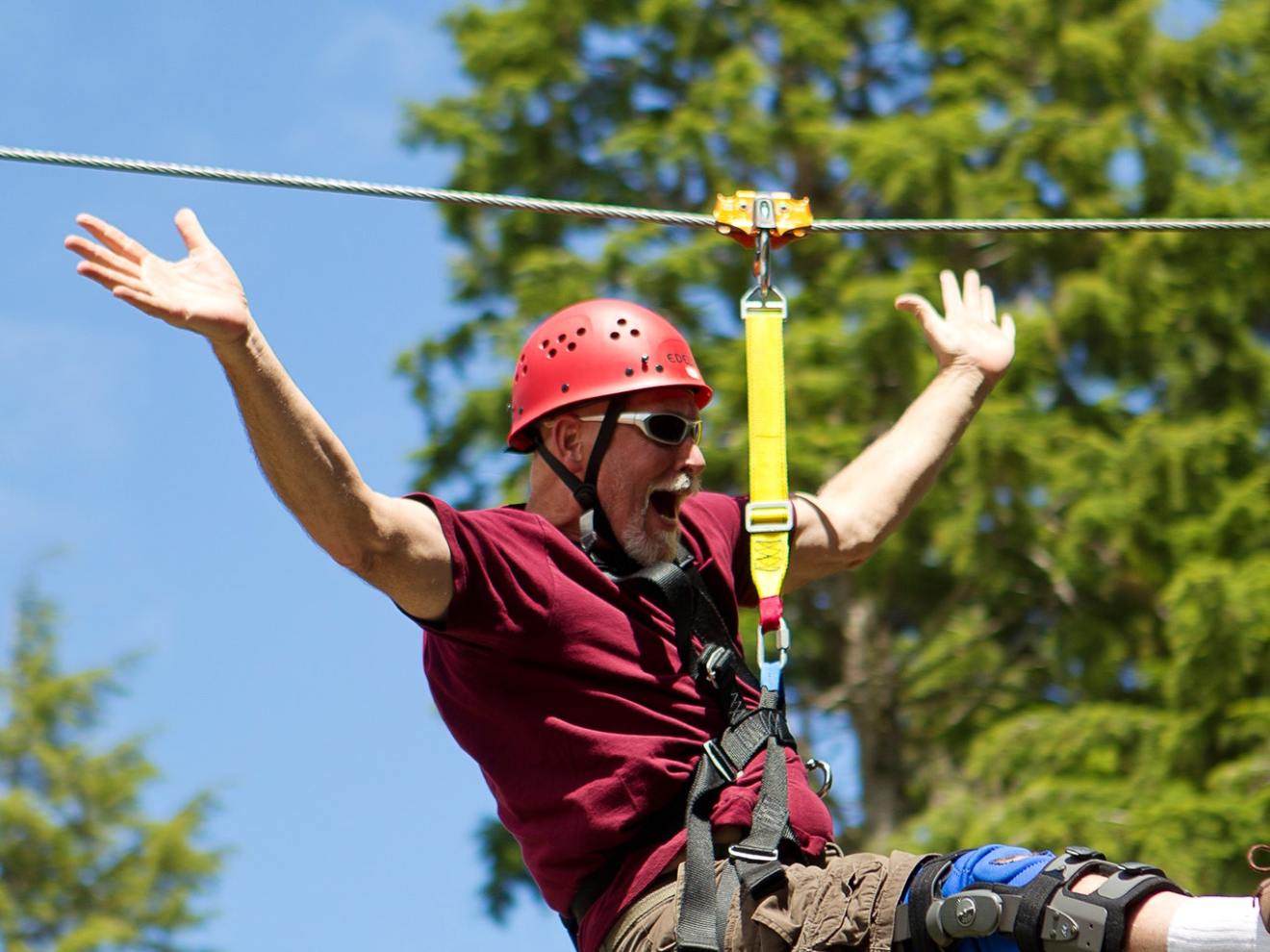 A man cheering as he rides the zipline