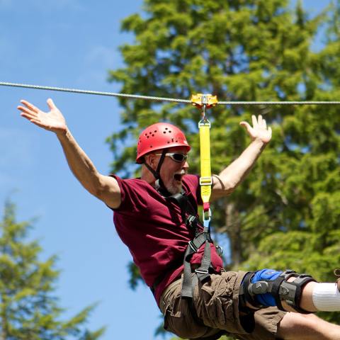 A man cheering as he rides the zipline