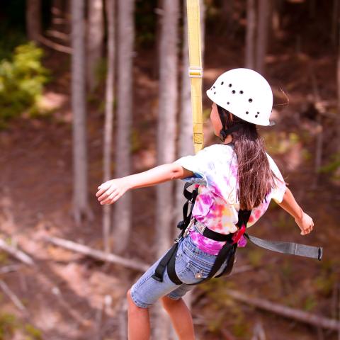 A girl ziplines with her arms outstretched