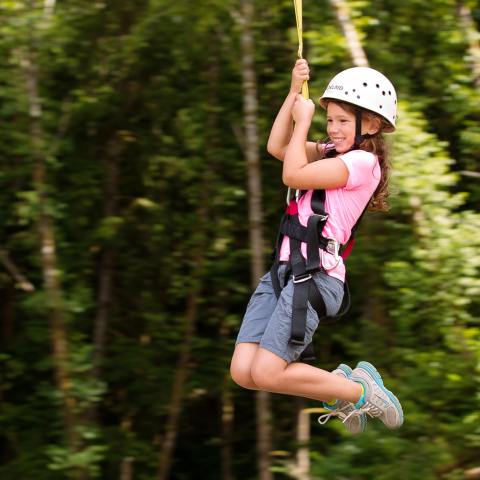 A girl smiles while she zip-lines with High Life Adventures