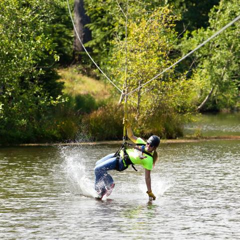 A woman skims over the water on the zipline