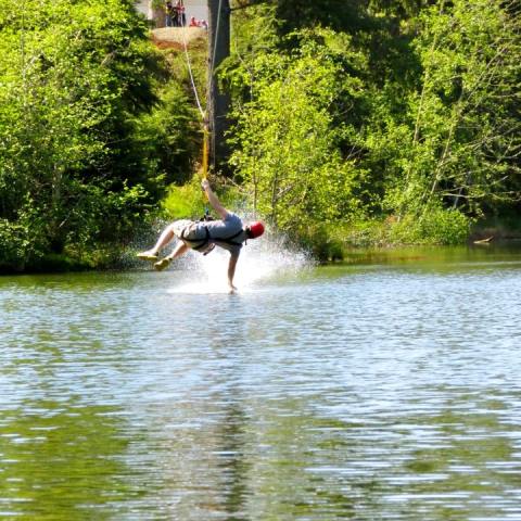 A zipliner skims the water on the Maple zipline