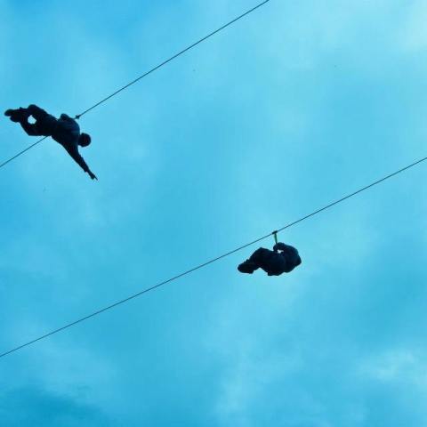 Two people ride the Spruce and Willow ziplines